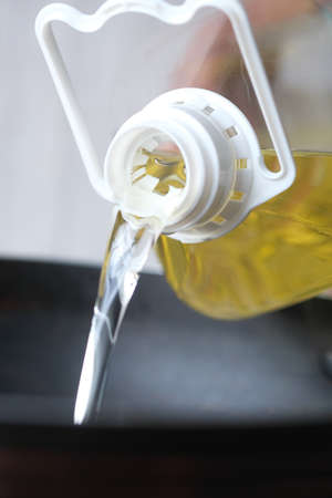 Pouring vegetable oil into frying pan.の写真素材