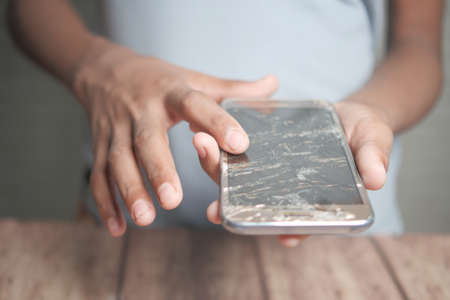 Close up of man hand holding broken smart phone.の写真素材