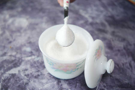white sugar and spoon in a container on black background,の写真素材