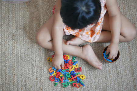child girl playing with colorful plastic lettersの写真素材