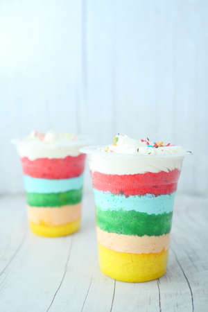 rainbow color cake in a plastic container on tableの写真素材