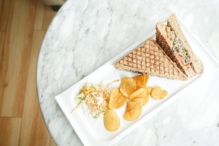 Tuna sandwich and chips on a plate on table ,