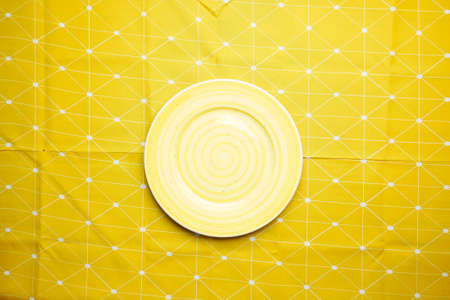 empty plate on a yellow color table cloth top viewの写真素材