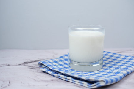 Close up of glass of milk and spoon on table