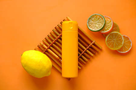 top view of sunscreen cream and lemon on orange backgroundの写真素材