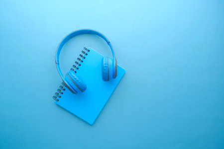 Audio book concept. Headphones and notepad on blue backgroundの写真素材