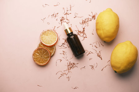 Essential oil bottle and lemon on yellow backgroundの写真素材