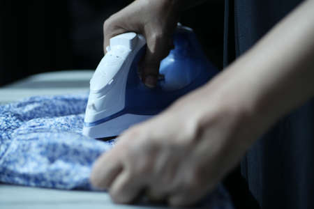 women hands ironing clothes with iron on ironing board.の写真素材