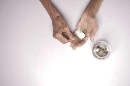 top view of senior women hand saving coins in a jarの写真素材