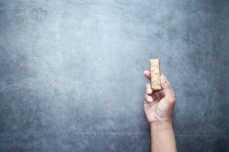 holding a Almond , Raisin and oat protein bars on black backgroundの写真素材