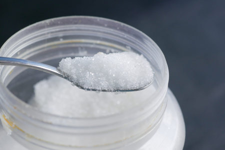 white sugar and spoon in a container on black background,