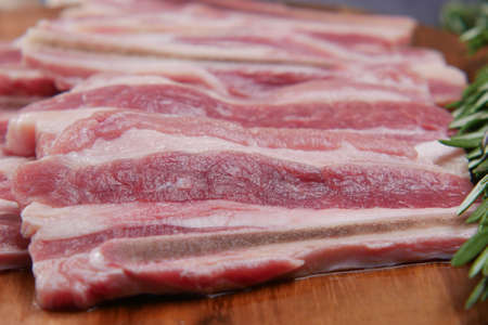 Raw fed bacon strips on chopping board .の写真素材