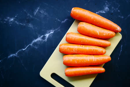 fresh carrots on chopping board on tableの写真素材
