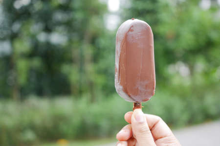 The woman holding the ice cream against green backgroundの写真素材