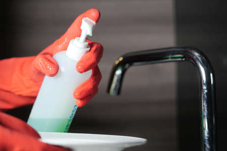 hand in gloves cleaning a white color plateの写真素材