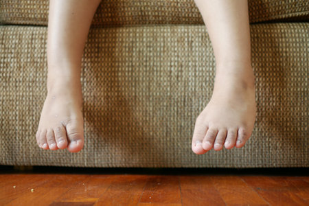 close up of 5 years old child dry feet sitting on sofaの写真素材