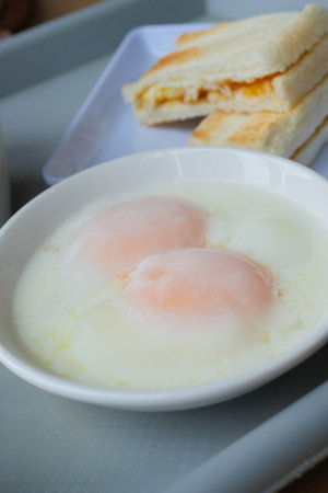 half boiled egg, toasted bread and tea on tableの写真素材
