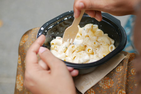 women eating take away cooked pasta in a plastic container