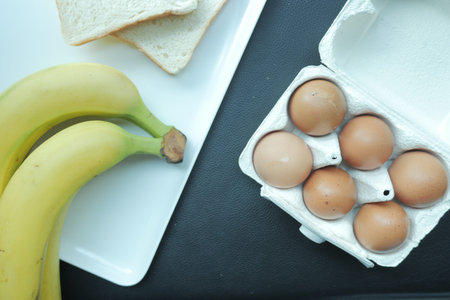 eggs in a container, bread and banana on table
