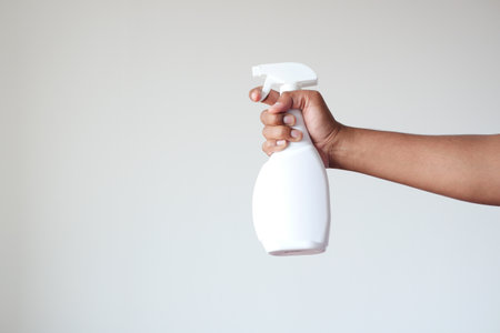 holding a white color disinfectant spray bottle against white wallの写真素材