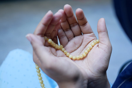 rear view of muslim women hand with rosary praying at ramadan