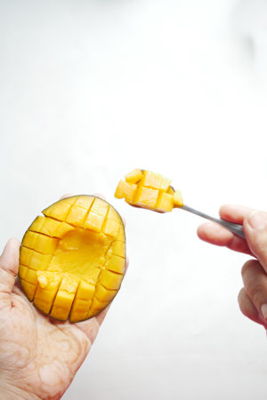 person hand cutting a mango with a spoonの写真素材