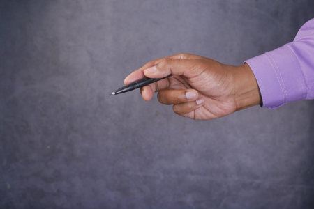 side view of holding a pen pointing something against black backgroundの写真素材
