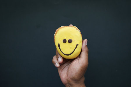 holding a smile face design donuts against black backgroundの写真素材