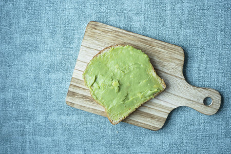 avocado spread on a bread on chopping boardの写真素材