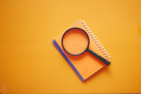 open book and magnifying glass on orange color backgroundの写真素材