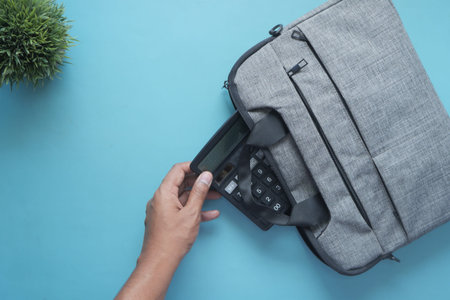 top view of young man putting office stationary in his bag
