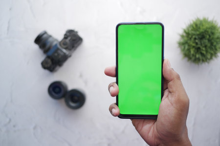 top view of holding smart phone with green screen and camera on backgroundの写真素材