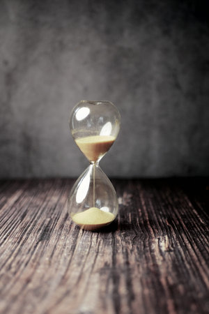 hourglass on table, sand flowing through the bulb of sandglass