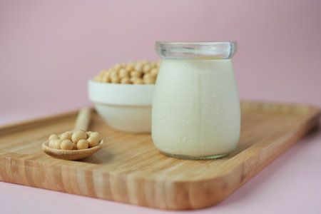 soy milk pouring in a glass jar on light pin backgroundの写真素材
