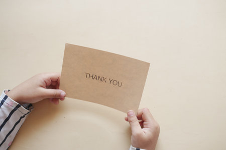 child hand holding thank you letter on tableの写真素材
