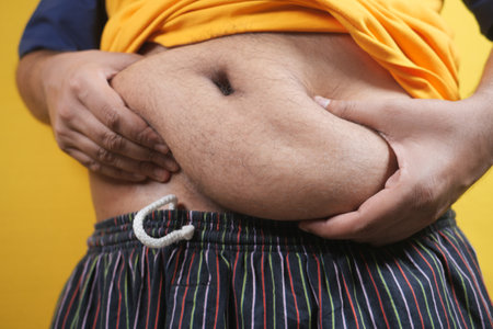 mans hand holding excessive belly fat, overweight conceptの写真素材