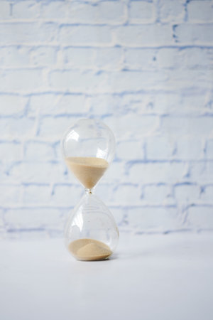 hourglass on table, sand flowing through the bulb of sandglass