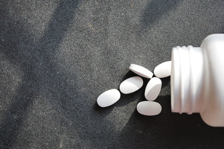 white color medical pills spilling on pink