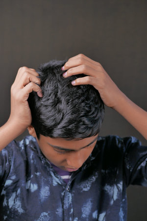 teenage boy Scratching Head Against black background .