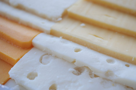 sliced cheese with holes on a chopping board on table
