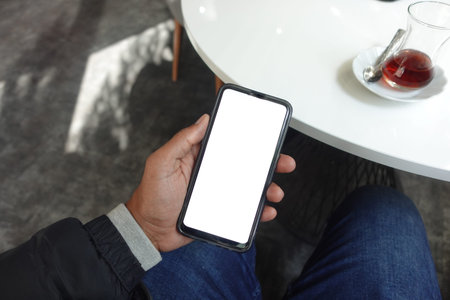 young man hand using smart phone with green screen at cafe