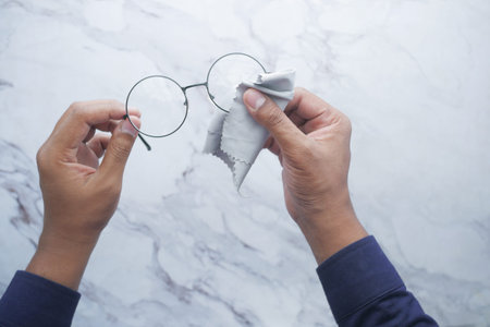 cleaning eyeglass with tissue close up