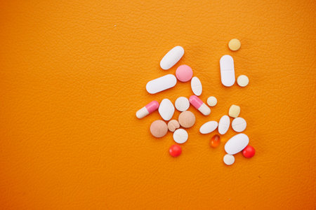 Close up of many colorful pills and capsules on orange backgroundの写真素材