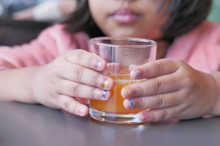 child holding a glass of orange juice close upの写真素材