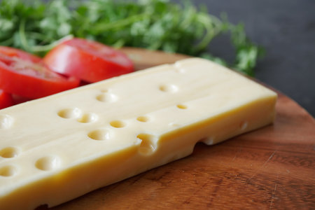 sliced cheese with holes on a chopping board on tableの写真素材