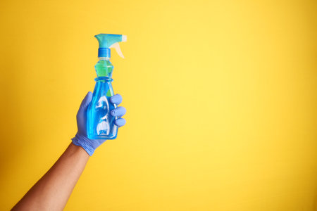 holding a plastic cleaning bottle against yellow backgroundの写真素材