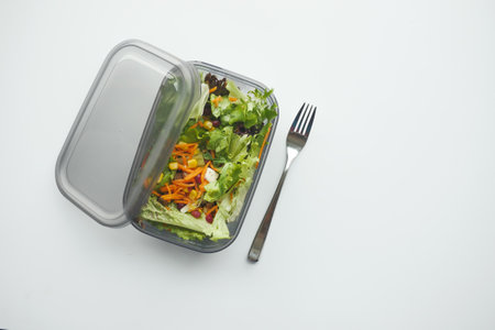top view of a lunch box with fresh salad on white tableの写真素材
