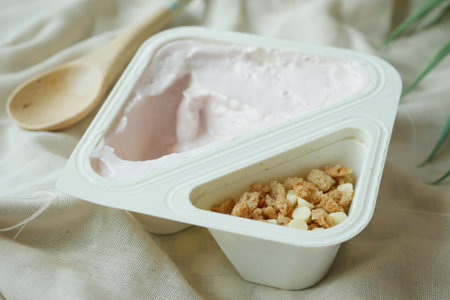 fresh yogurt in a plastic container and spoon on tableの写真素材