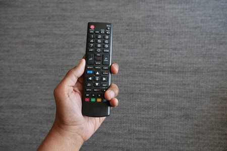 close up of man hand holding tv remote.