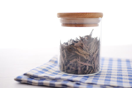 Dry tea leaves in a container on whiteの写真素材